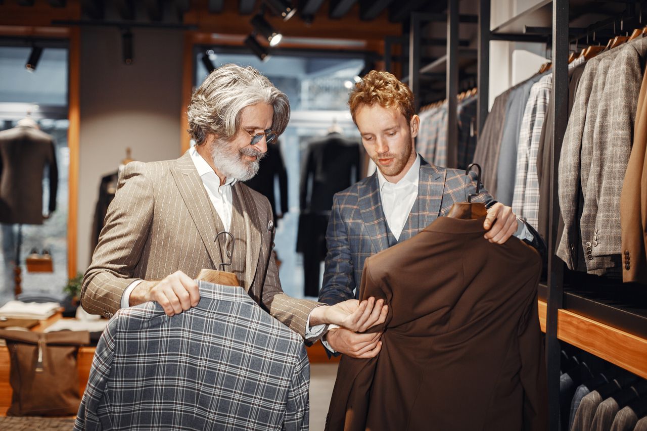 Two men selecting suits in a modern fashion boutique, highlighting style and elegance.