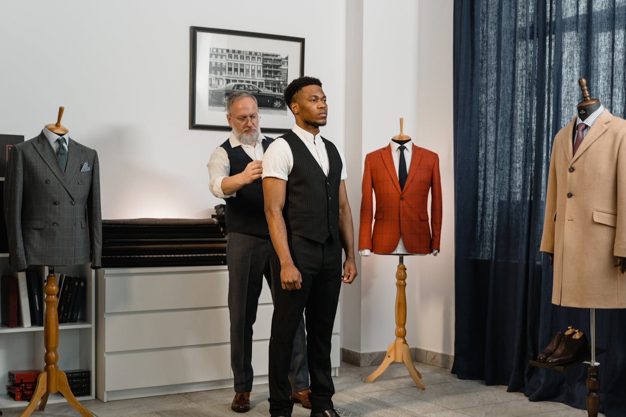 Tailor measuring a client's suit in an elegant indoor setting for custom fit.