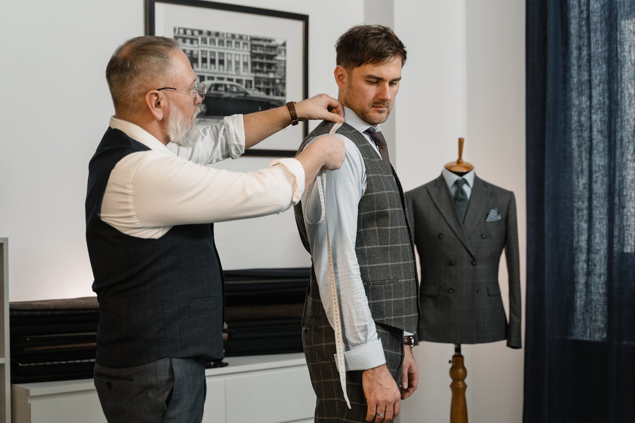 Tailor expertly measuring client for a custom-made suit in a stylish workshop.